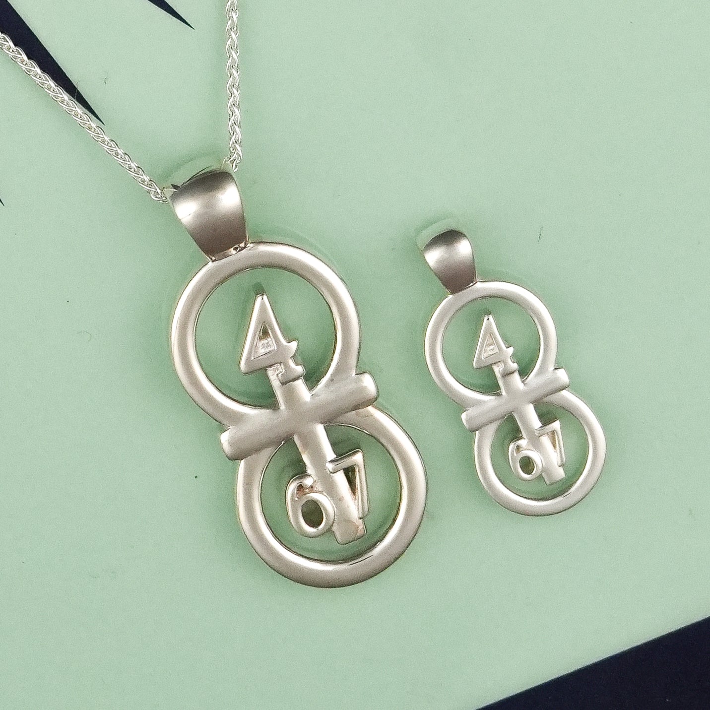 The silver RIYAN 29 and 11® pendant has the numbers 4,6, and 7 intertwined with the cross to represent Philippians 4:6-7 with the chapter name "Phillipians" inscribed on the back.