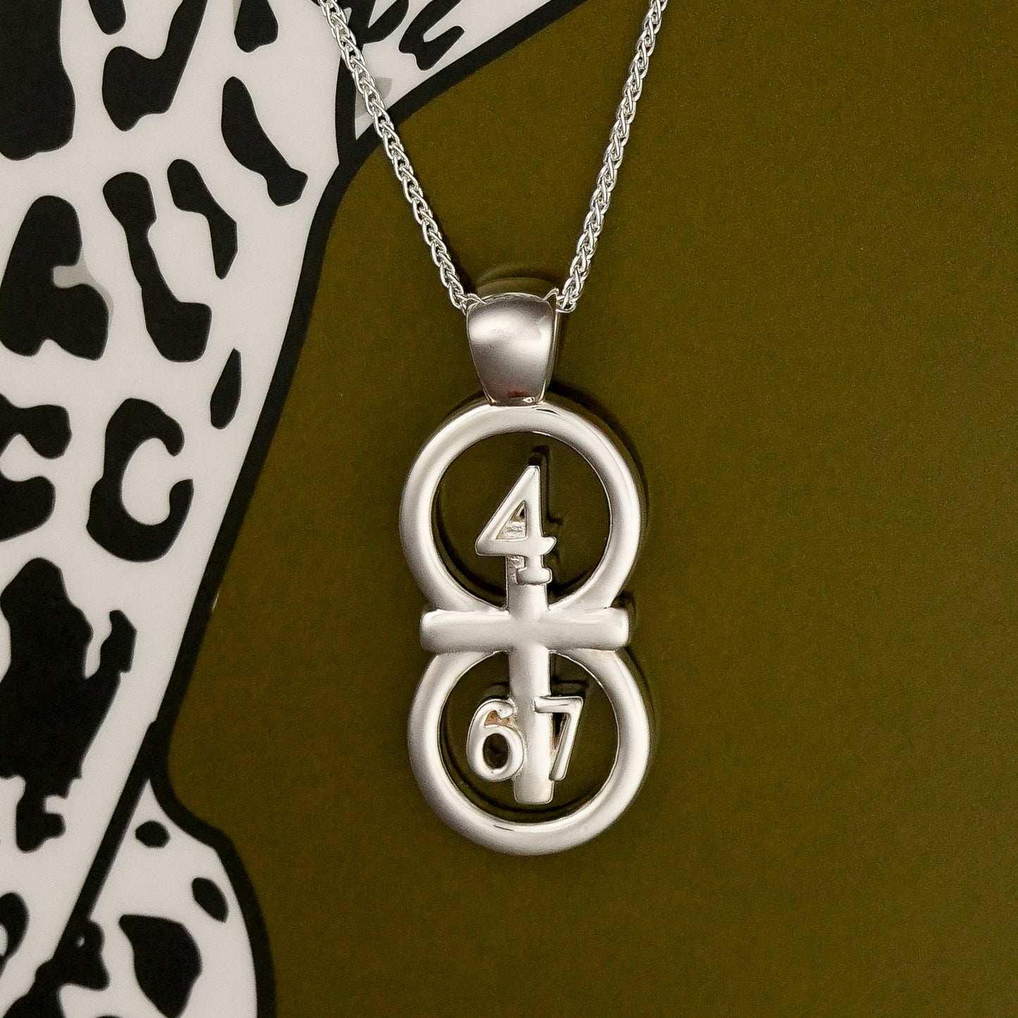 The silver RIYAN 29 and 11® pendant has the numbers 4,6, and 7 intertwined with the cross to represent Philippians 4:6-7 with the chapter name "Phillipians" inscribed on the back.