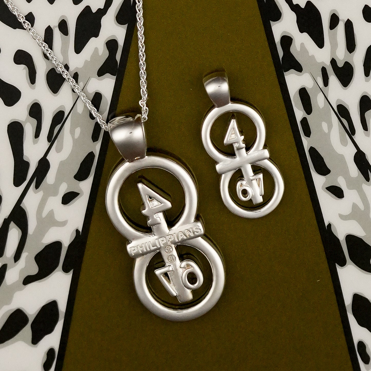 The silver RIYAN 29 and 11® pendant has the numbers 4,6, and 7 intertwined with the cross to represent Philippians 4:6-7 with the chapter name "Phillipians" inscribed on the back.