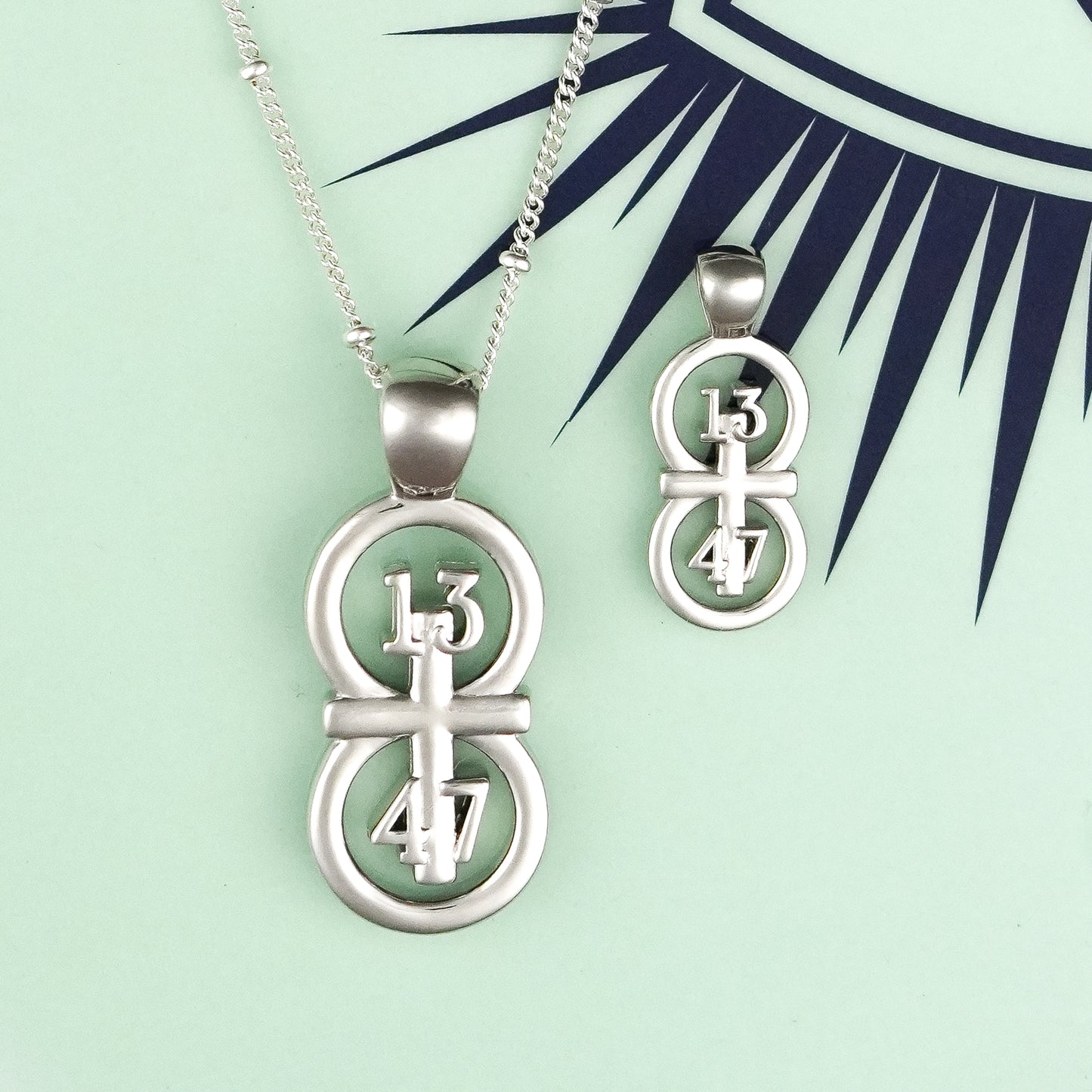 The silver RIYAN 29 and 11® pendant has the numbers 13, 4, and 4 intertwined with the cross to represent 1 Corinthians 13:4-7 with the chapter word "1 Corinthians" inscribed on the back.