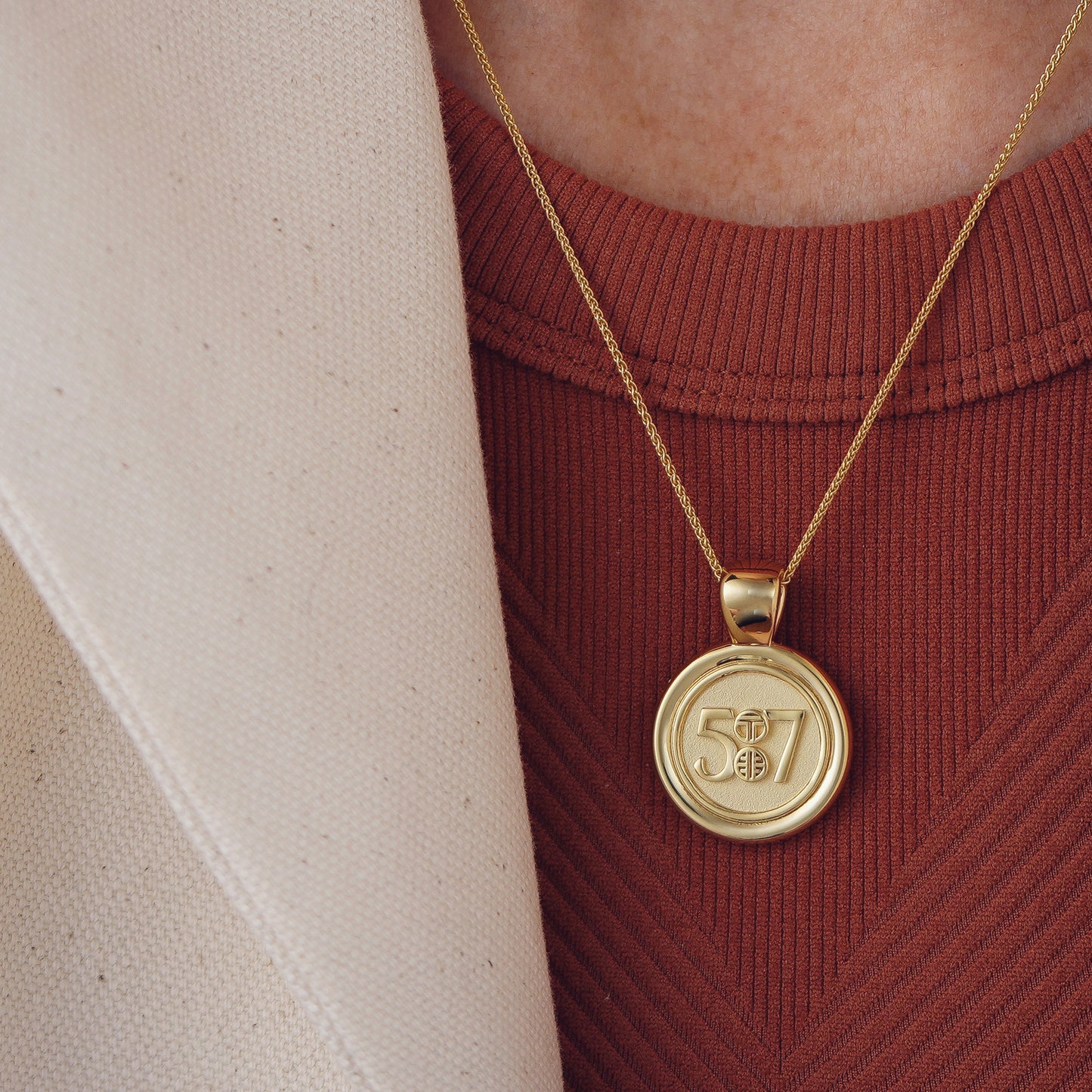 The WYIT is our first reversible pendant.&nbsp; One side of the medallion has the numbers 5 and 7 with our logo displayed as the colon between the chapter and verse.&nbsp; &nbsp;The other side of the pendant has a raised two tier cross. Down the vertical side of the pendant the chapter name 2 Corinthians is inscribed on the medallion.  Model is wearing the pendant on our 18" Wheat chain .  Model is wearing a burnt red high neck tank & blazer.