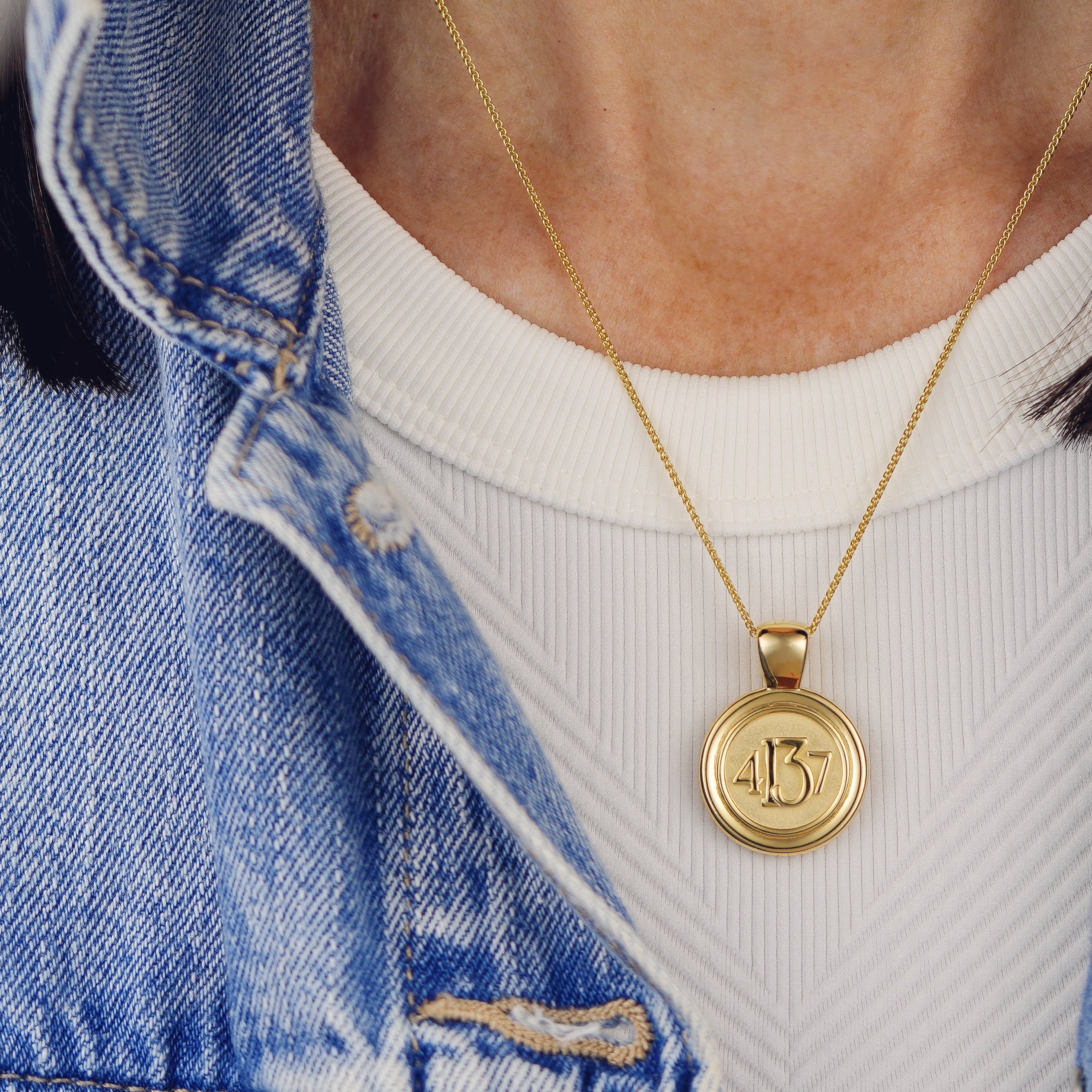 The WYIT Pendant Corinthians 13:4-7.  Model is wearing the pendant on our 18" wheat chain against a white Free People Movemint tank and denim jacket.