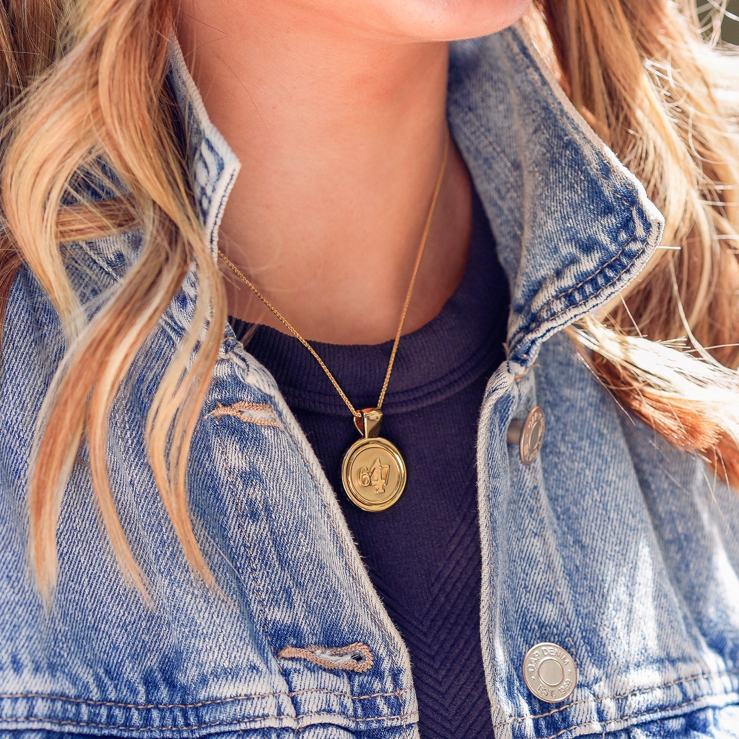 The WYIT is our first reversible pendant. One side of the medallion has the number 4 in the center of the pendant with the numbers 6 and 7 on each side. The other side of the pendant has a raised two tier cross. Down the vertical side of the pendant the chapter name Philippians is inscribed on the medallion.  Model is wearing a navy blue tank with an denim jacket with WYIT pendant on an 18" wheat chain.
