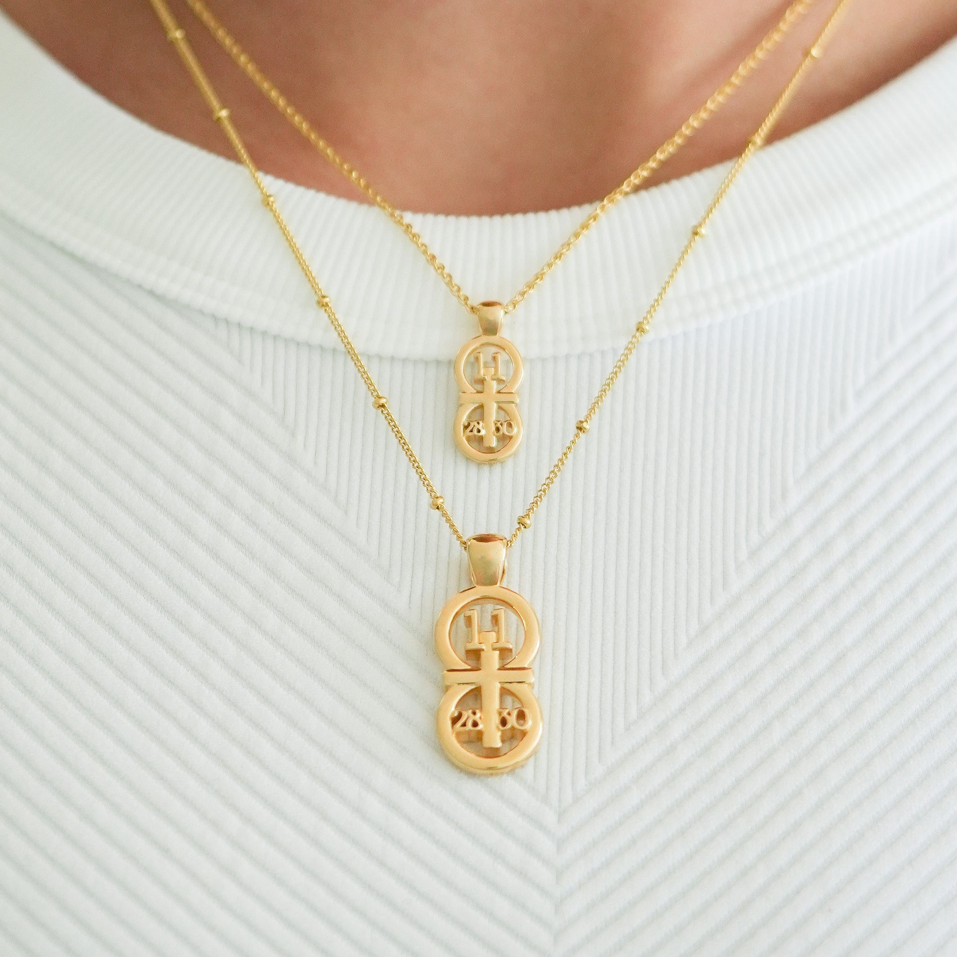 Gold small and large pendants displayed on neck with this wheat chain and satellite chain on the larger pendant.  The RIYAN 29 and 11® pendant has the numbers 11, 28, and 30 intertwined with the cross to represent Matthew 11:28-30 with the chapter word "Matthew" inscribed on the back.