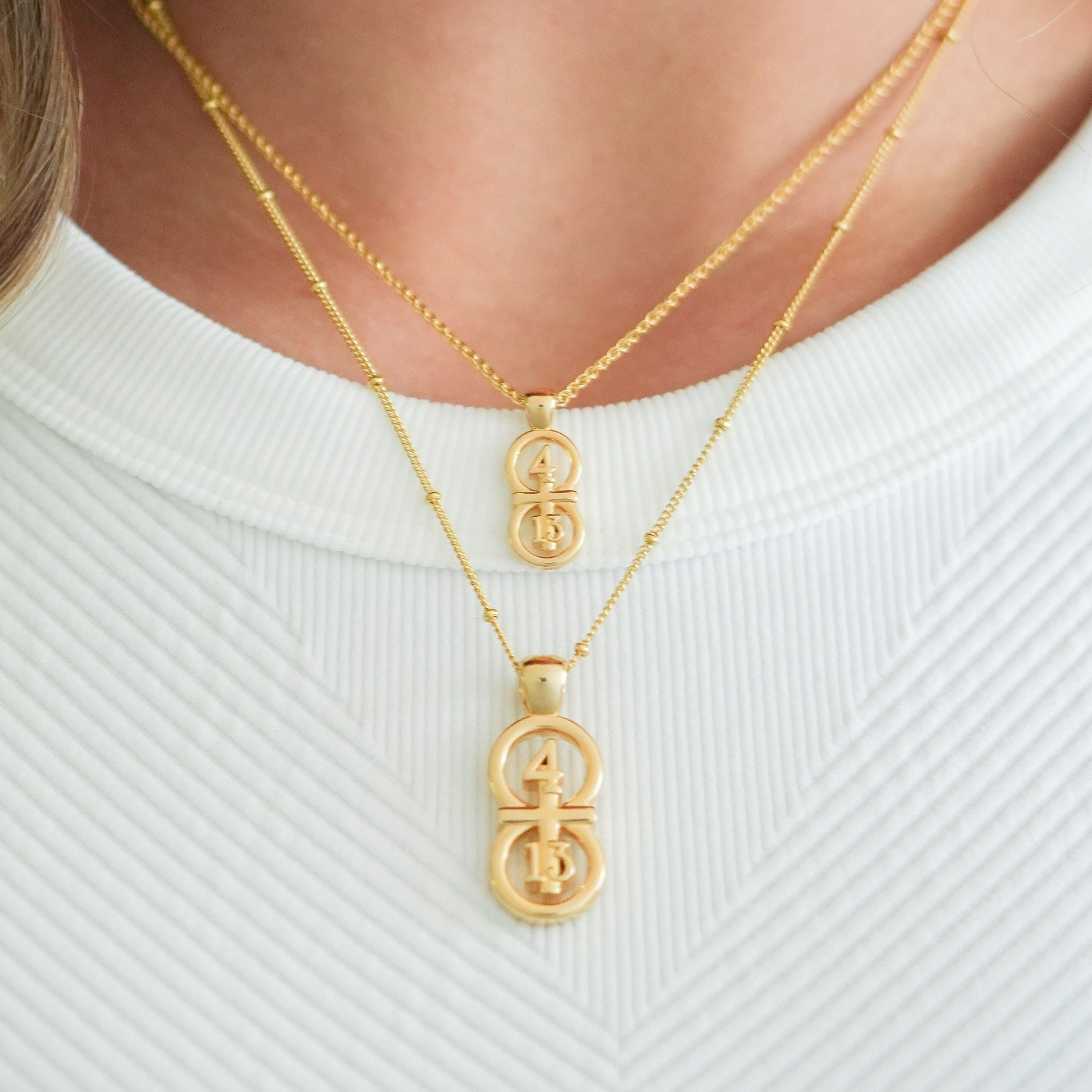 Gold small and large pendants displayed on neck with this wheat chain and satellite chain on the larger pendant.  Our 29 and 11® pendant has the numbers 4 and 13 intertwined with the cross to represent Philippians 4:13 with the chapter word "Philippians" inscribed on the back.