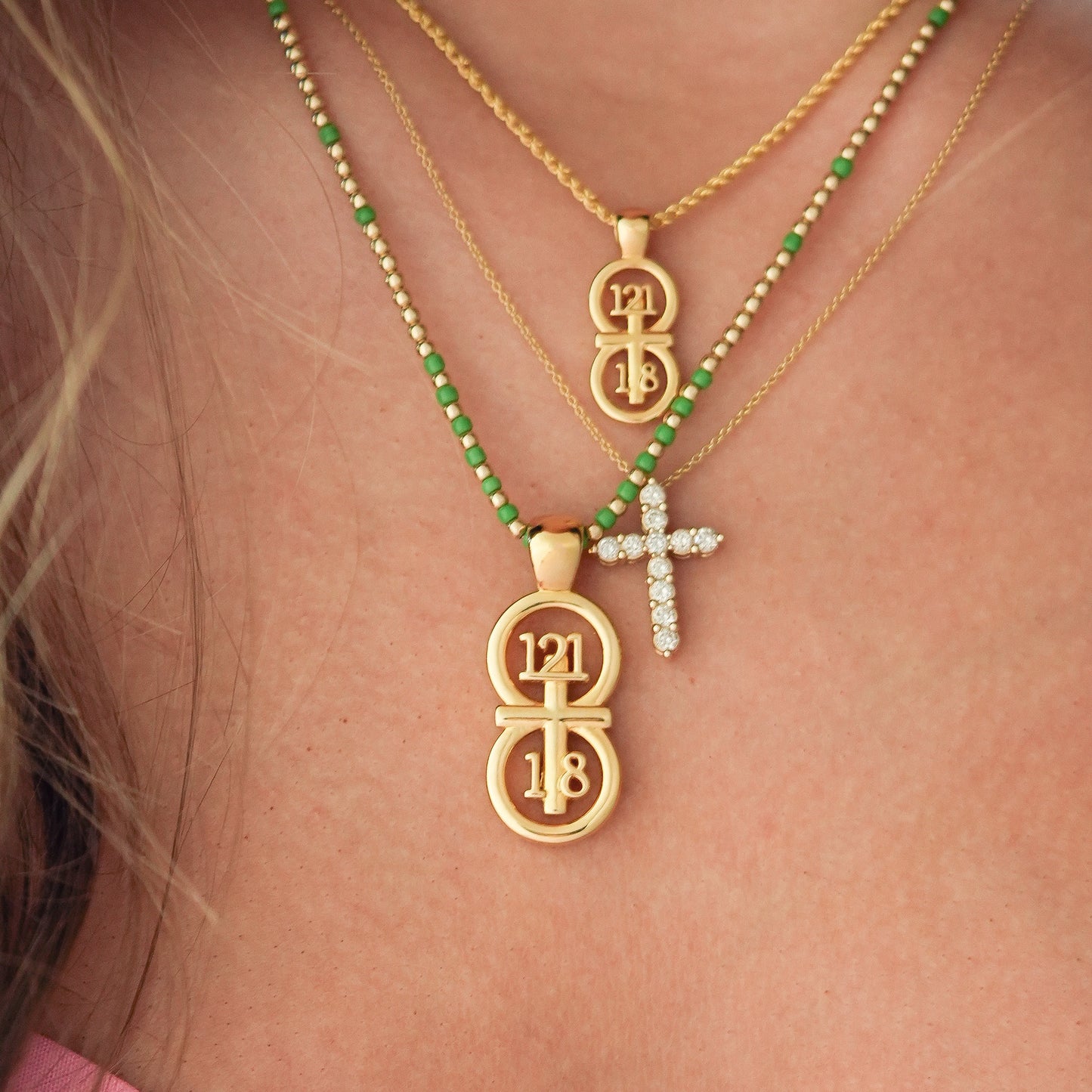 Lifestyle picture - three necklaces are displayed - our small Psalm 121:1-8 pendant on our 14k gold filled wheat chain, a diamond cross purchased from Croghan’s in Charleston, and our large Psalm 121:1-8 pendant on our hand beaded kelly green gold chain. The RIYAN 29 and 11® pendant has the numbers 121, 1, and 8 intertwined with the cross to represent Psalm 121:1-8 with the chapter word "Psalm" inscribed on the back.